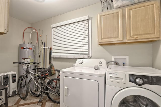 laundry room with cabinets, washing machine and dryer, and water heater