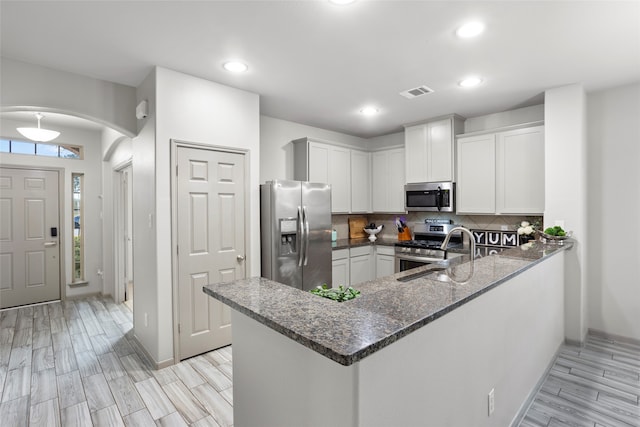 kitchen with kitchen peninsula, appliances with stainless steel finishes, light hardwood / wood-style flooring, and white cabinetry