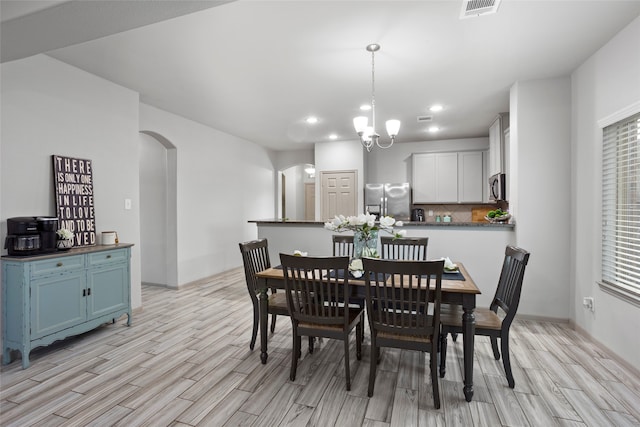 dining area featuring light wood-type flooring and an inviting chandelier