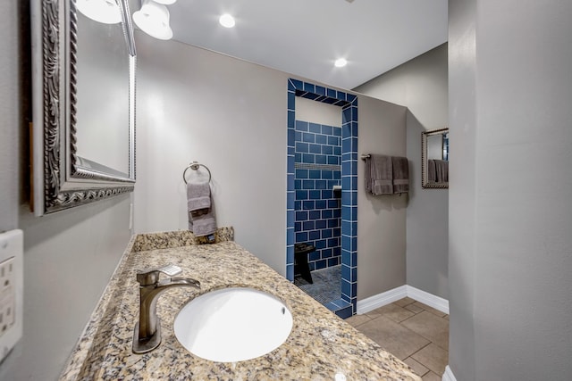 bathroom with tiled shower, vanity, and tile patterned floors