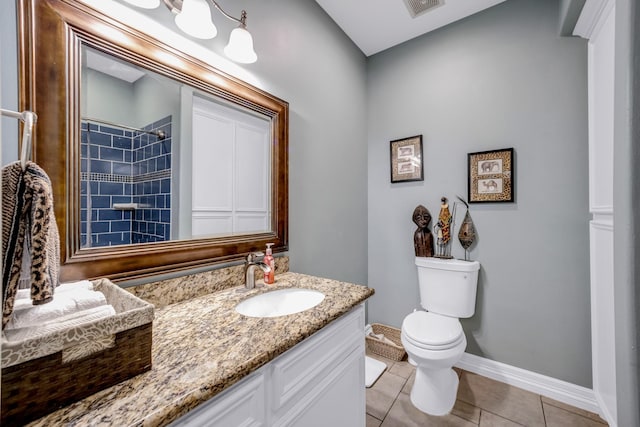 bathroom featuring tile patterned floors, vanity, tiled shower, and toilet