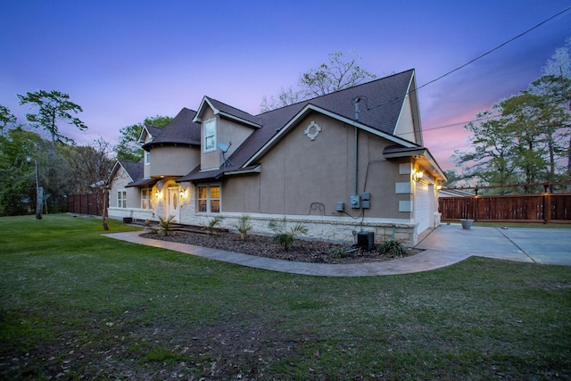 property exterior at dusk featuring a garage and a lawn