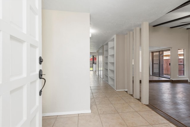 hall with light tile patterned flooring and a textured ceiling