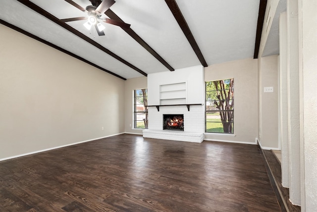 unfurnished living room featuring lofted ceiling with beams, dark hardwood / wood-style floors, a brick fireplace, and ceiling fan