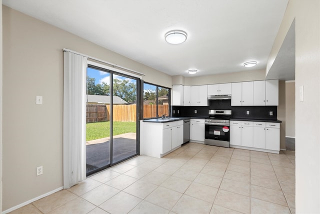 kitchen with white cabinets, light tile patterned floors, stainless steel appliances, and tasteful backsplash