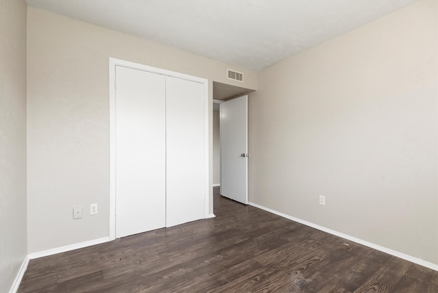 unfurnished bedroom featuring dark hardwood / wood-style floors and a closet