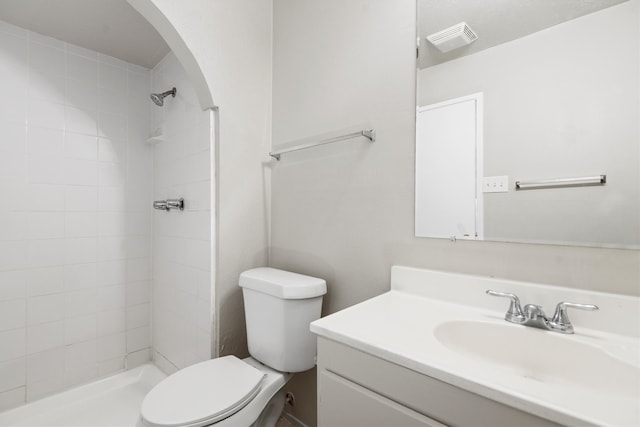 bathroom featuring tiled shower, vanity, and toilet