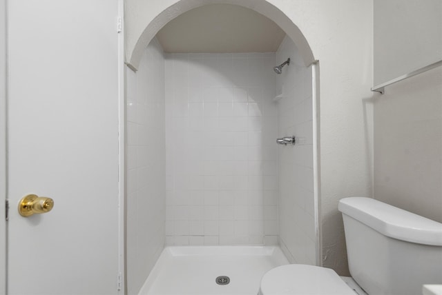 bathroom featuring toilet and tiled shower