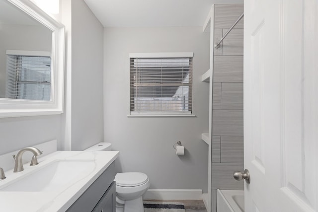 full bathroom featuring tiled shower / bath, vanity, and toilet