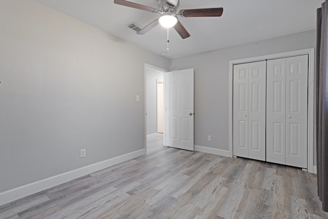 unfurnished bedroom with ceiling fan, light wood-type flooring, and a closet