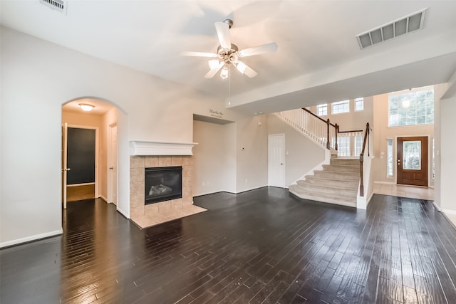 unfurnished living room with dark hardwood / wood-style floors, ceiling fan, a high ceiling, and a tiled fireplace