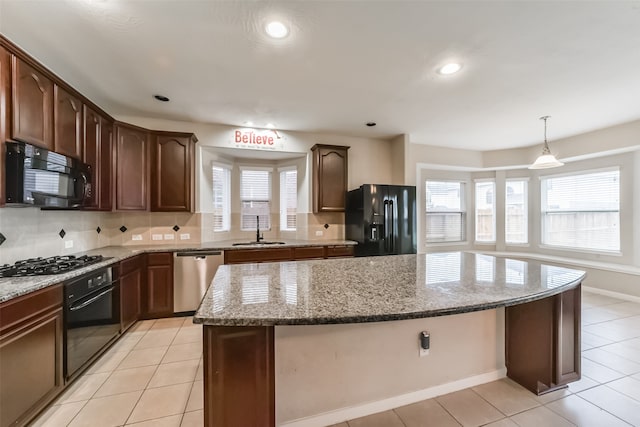 kitchen with sink, a kitchen island, a wealth of natural light, and black appliances