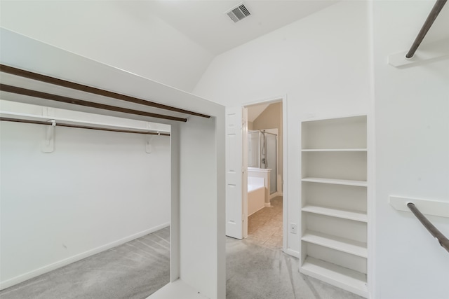 walk in closet with lofted ceiling and light carpet