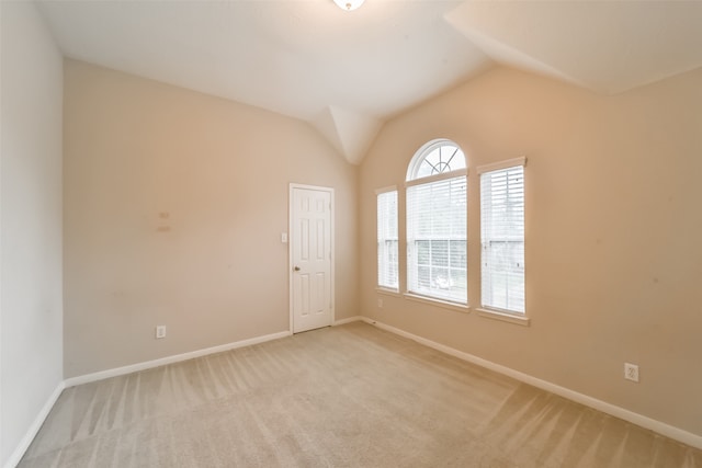 carpeted spare room featuring vaulted ceiling