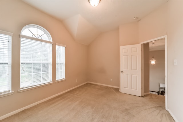 carpeted spare room with vaulted ceiling