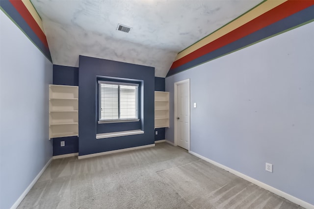 carpeted empty room featuring lofted ceiling