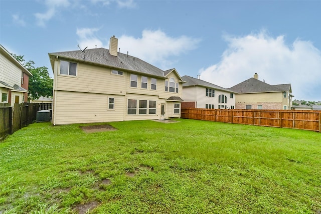 back of property featuring a yard, central AC, a fenced backyard, and a chimney