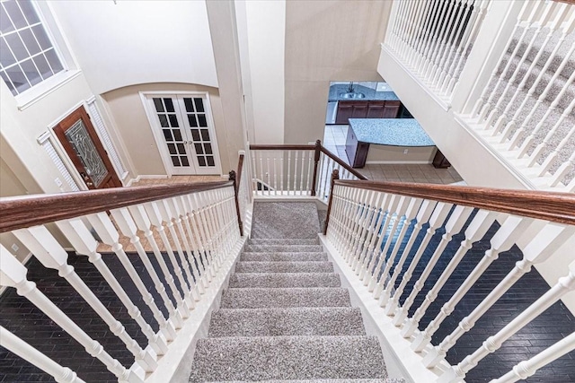 stairs with french doors, arched walkways, and a towering ceiling
