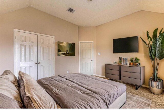 bedroom featuring a closet, visible vents, light colored carpet, and lofted ceiling