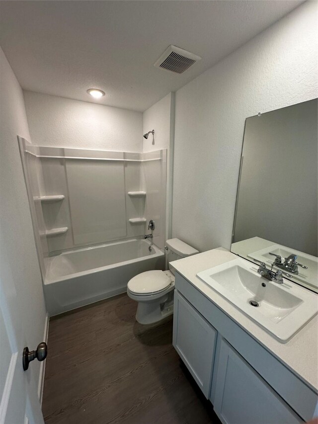 full bathroom featuring washtub / shower combination, hardwood / wood-style floors, vanity, and toilet