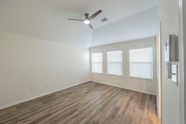 unfurnished room featuring lofted ceiling, visible vents, a ceiling fan, wood finished floors, and baseboards