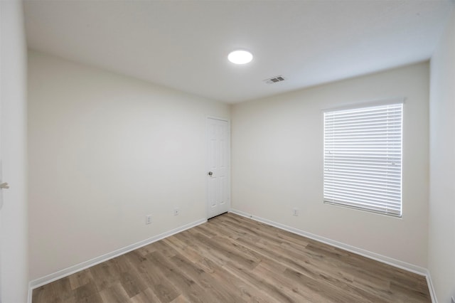 unfurnished room featuring light wood finished floors, visible vents, and baseboards