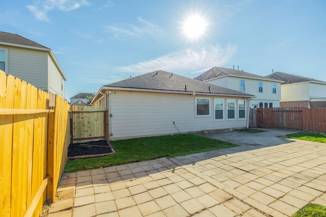 back of house featuring a patio, roof with shingles, and a fenced backyard