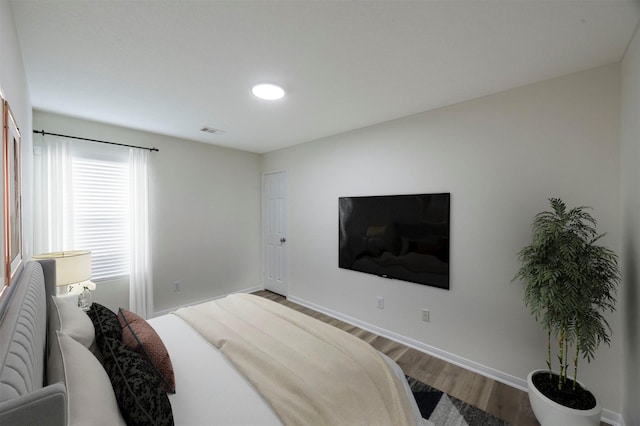 bedroom with wood finished floors, visible vents, and baseboards