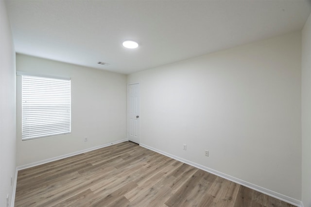 empty room with light wood-type flooring, baseboards, and visible vents