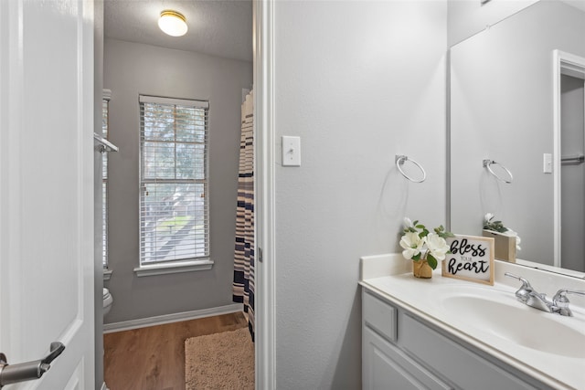 bathroom featuring toilet, vanity, a textured ceiling, and hardwood / wood-style flooring