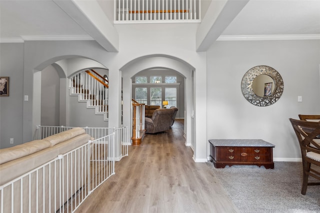 hallway with light wood-type flooring and ornamental molding