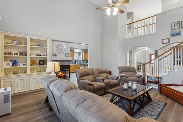 living room with a towering ceiling, hardwood / wood-style flooring, and ceiling fan