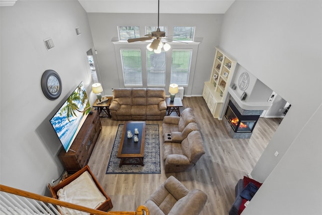 living room featuring ceiling fan, a high ceiling, and hardwood / wood-style flooring