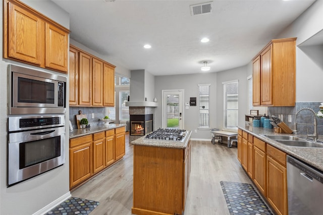 kitchen with light wood-type flooring, a center island, stainless steel appliances, and sink