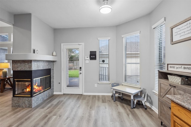 interior space with light hardwood / wood-style flooring and a tiled fireplace