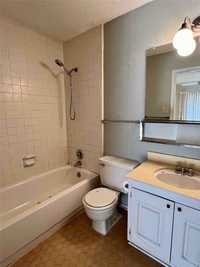 full bathroom featuring vanity, a textured ceiling, toilet, and tiled shower / bath