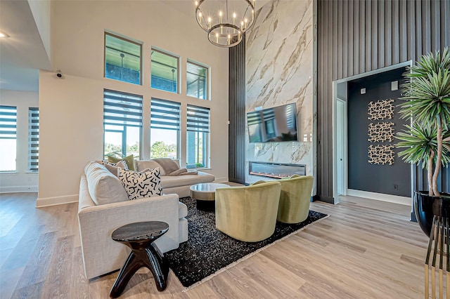 living room with a premium fireplace, a healthy amount of sunlight, a chandelier, and light wood-type flooring