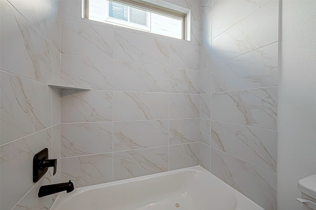 bathroom featuring tiled shower / bath and toilet