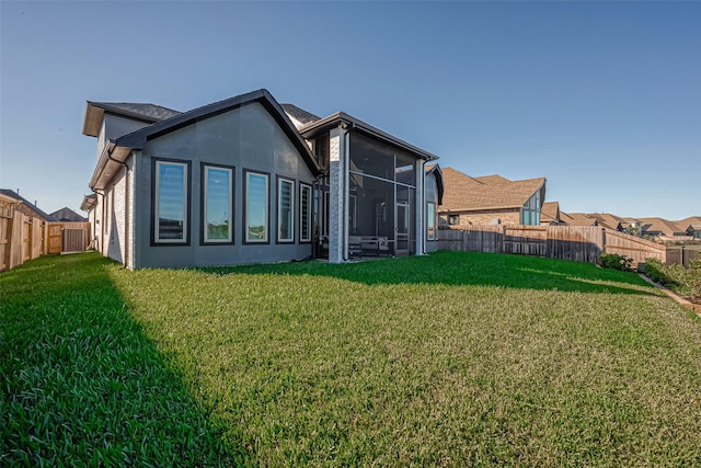 back of property with a yard and a sunroom