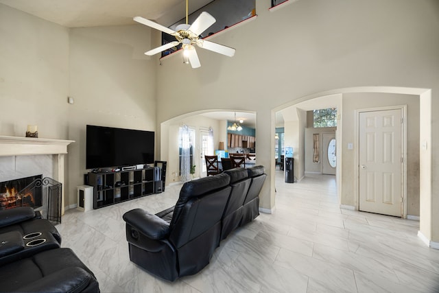 living room featuring a fireplace, ceiling fan with notable chandelier, high vaulted ceiling, and a wealth of natural light