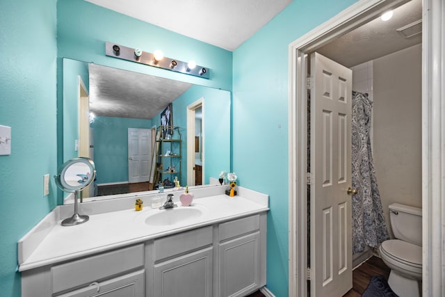 bathroom with walk in shower, a textured ceiling, vanity, hardwood / wood-style flooring, and toilet