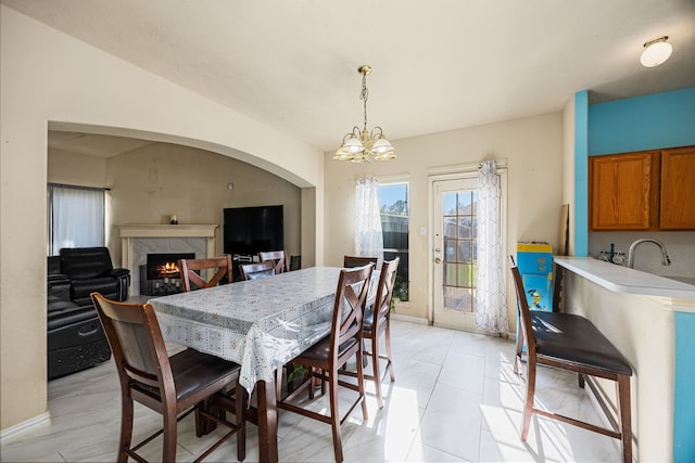 tiled dining space with sink, a fireplace, and an inviting chandelier