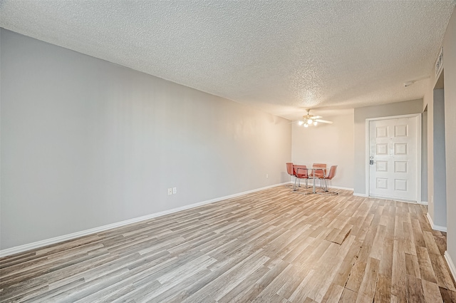 spare room with ceiling fan, light hardwood / wood-style floors, and a textured ceiling