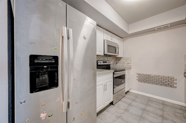 kitchen with backsplash, white cabinetry, stainless steel appliances, and light tile patterned floors