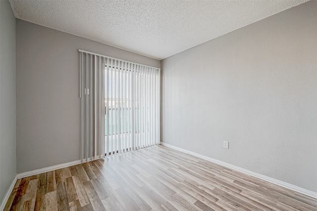 spare room with a textured ceiling and light hardwood / wood-style flooring