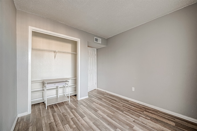 unfurnished bedroom featuring a closet, a textured ceiling, and hardwood / wood-style flooring