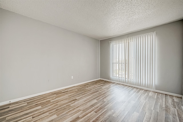 empty room featuring light wood-type flooring and a textured ceiling