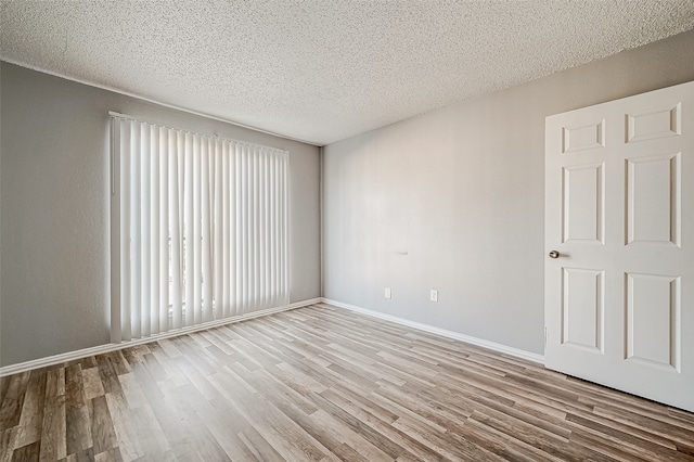 empty room featuring a healthy amount of sunlight, a textured ceiling, and light wood-type flooring