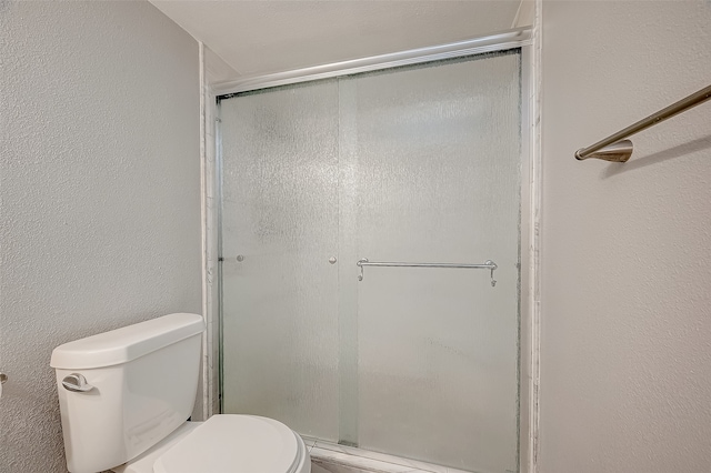 bathroom featuring toilet and a shower with shower door