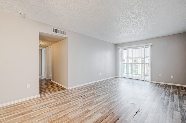 spare room with a textured ceiling and light hardwood / wood-style flooring